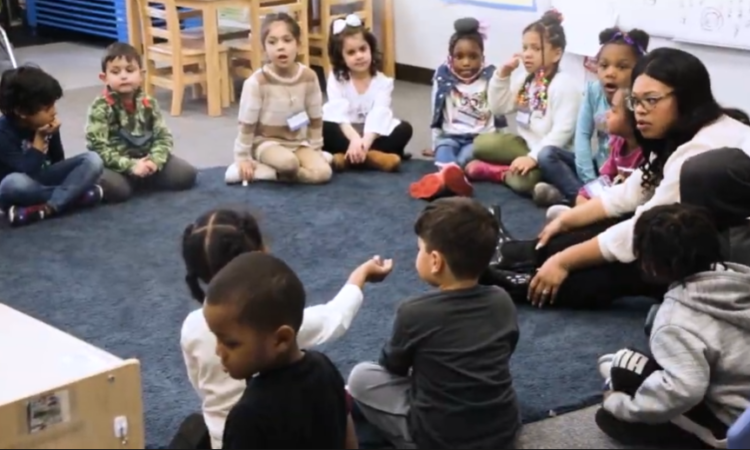 Group of preschool kids in circle on floor with teacher