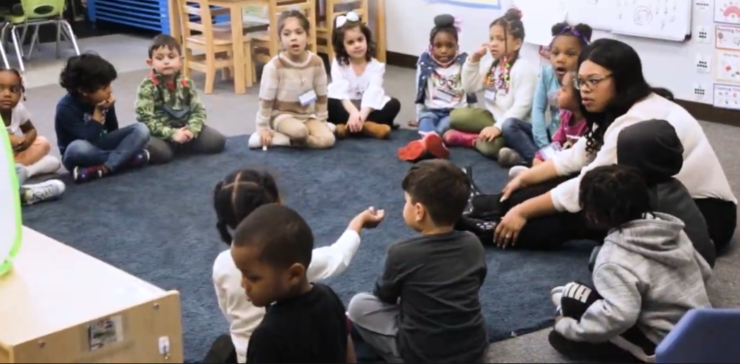 Group of preschool kids in circle on floor with teacher